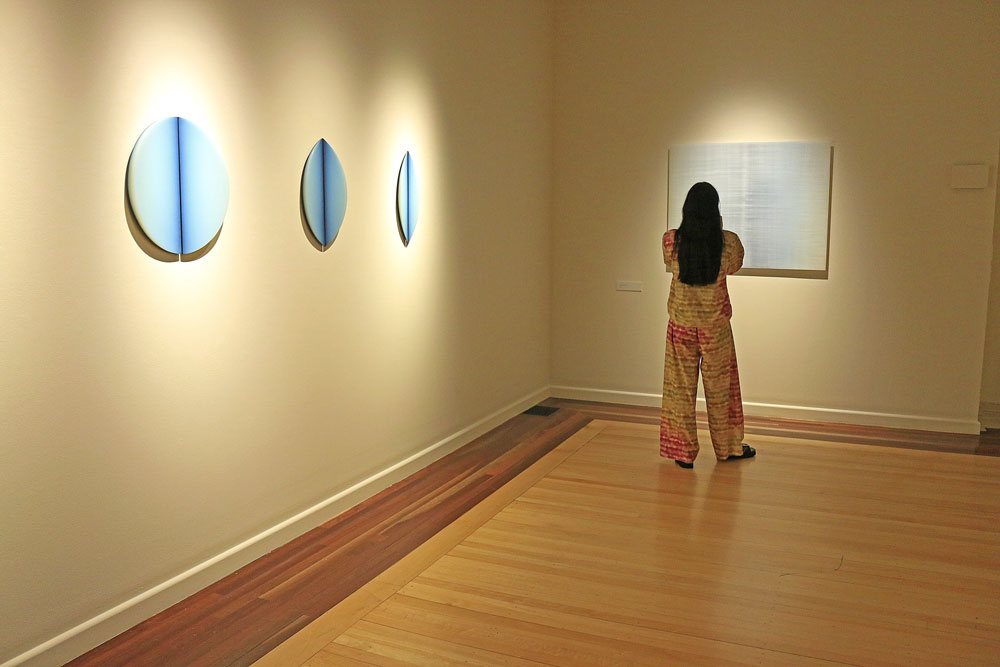 A lady inspects some artwork depicting light at the Cairns Art Gallery. 